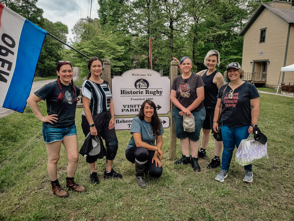 Historic Rugby sign with Katie Brittle, Jennifer Wyatt, Miranda Young, Amber, Diana Doty, and Becky Kilimnik